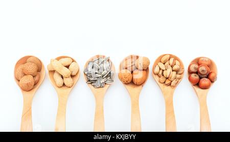 Divers écrous dans des cuillères en bois sur fond blanc Banque D'Images