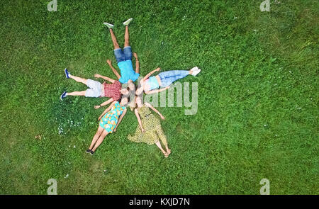 Groupe de jeunes adultes laying in grass dans la formation des étoiles Banque D'Images