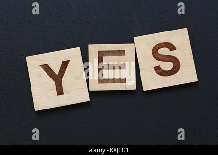 Close up mot oui sur lettre de scrabble en bois noir sur fond d'affiches Banque D'Images