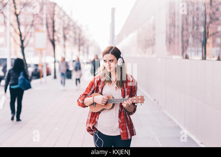 Jeune femme dans la ville à l'ukulele - musicien ambulant, musicien, compositeur concept Banque D'Images