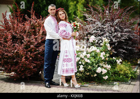 Cute couple de mariage vêtements traditionnels ukrainiens en posant à côté des buissons dans le parc. Banque D'Images