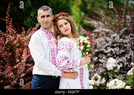 Cute couple de mariage vêtements traditionnels ukrainiens en posant à côté des buissons dans le parc. Banque D'Images