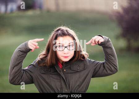 Portrait of Girl in spectacles pointant sur son visage Banque D'Images