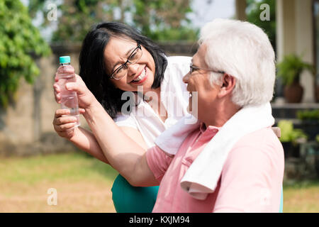 Attention senior woman donner un biberon d'eau à son partenaire out Banque D'Images