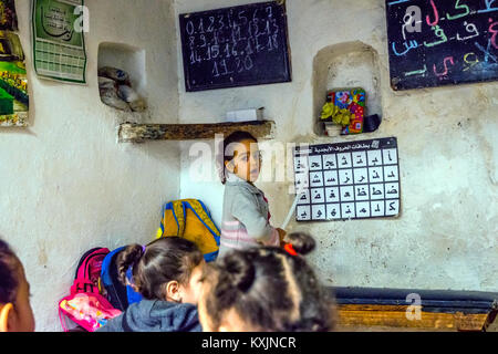 Fes, MAROC - 10 DÉCEMBRE : School girl debout devant la classe et en pointant sur l'alphabet en lettres arabes de l'école locale de Fès. Décembre 2016 Banque D'Images