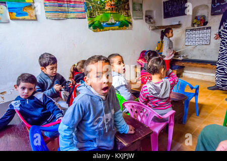 Fes, MAROC - 10 DÉCEMBRE : School girl debout devant la classe et en pointant sur l'alphabet en lettres arabes de l'école locale de Fès. Décembre 2016 Banque D'Images