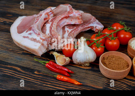Steak de porc cru - prête pour la cuisson avec des herbes. Les steaks de porc cru fond gris sur planche de bois d'épices Banque D'Images