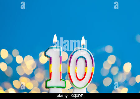 Numéro 10 Un anniversaire bougie contre une lumière vive et le fond bleu Banque D'Images