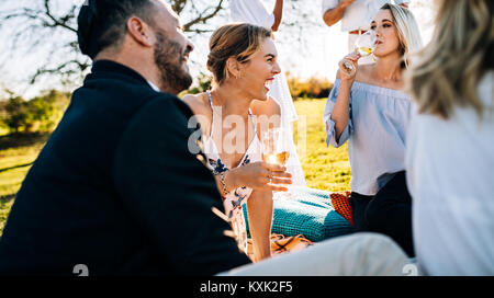Très bon moment avec vos amis. Les jeunes gens joyeux à discuter et boire du vin tout en restant assis dans le restaurant le jardin. Banque D'Images