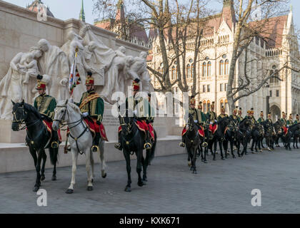 Hussards sur les chevaux en face de la Maison du Parlement pendant la parade du 15 mars à Budapest, Hongrie. Cavalerie hussard en fête traditionnelle uniforme. Banque D'Images