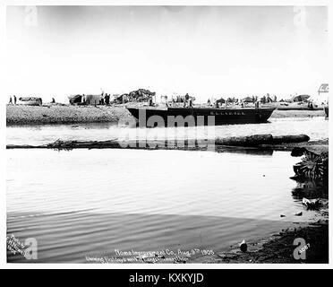 La photographie représente une barge, des tentes et un groupe de personnes sur la plage de Nome, en Alaska, en août 1905, illustrant la vie côtière et les activités de peuplement au début du XXe siècle. Banque D'Images