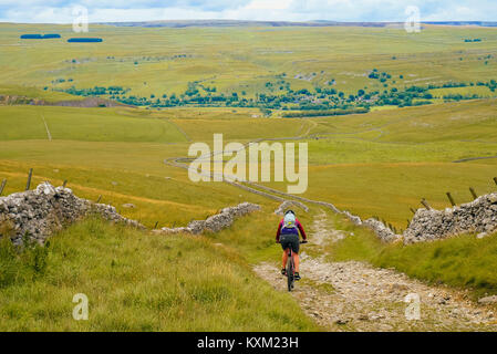 Vélo de montagne femelle sur le très connu Mastiles Lane dans le Yorkshire Dales, descendant vers Wharfedale Banque D'Images