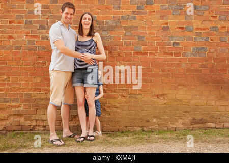 Portrait of pregnant woman et cacher la fille par brick wall Banque D'Images