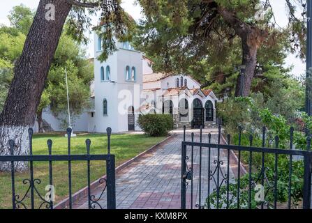 Vue d'une église orthodoxe grecque où un chemin pavé mène sous un arbre à l'entrée de l'église. Banque D'Images