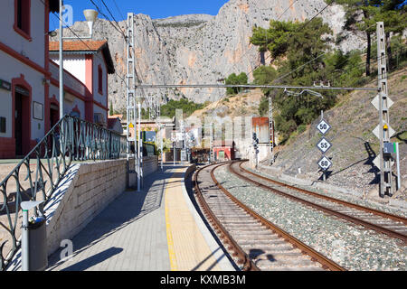 El Chorro gare en andalousie espagne avec des bâtiments peints une ligne de chemin de fer dans un tunnel en courbe et la roche dans le cadre d'un sk bleu Banque D'Images