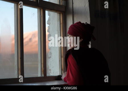 Pays rural mongol Kazakh côté jeune fille en regardant par la fenêtre d'hiver coucher de la Mongolie Banque D'Images