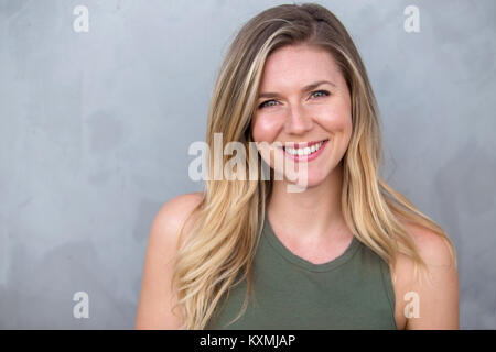 Superbe portrait de jeunes sincères joyeux lumineux smiling caucasian blonde sur un arrière-plan gris Banque D'Images