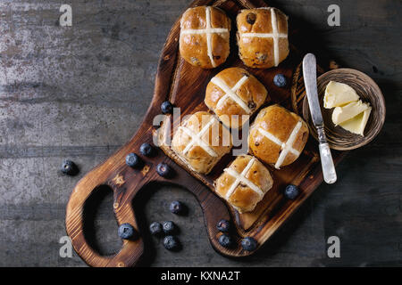 Les brioches sur planche à découper en bois servi avec du beurre, un couteau, des bleuets frais et pot de crème sur fond métal texture vieux. Vue de dessus, spac Banque D'Images