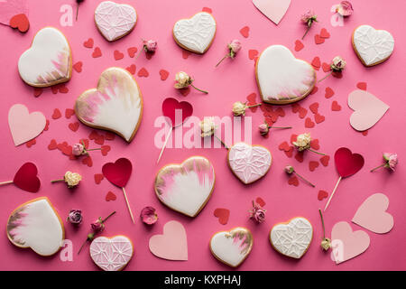 Mise à plat avec les cookies en forme de coeur, fleurs décoratives et isolé sur des coeurs en papier rose, st valentines day concept Banque D'Images