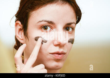 Redhead modèle à l'aide d'éponge exfoliante, masque charbon noir pour nettoyer et traiter sa peau Banque D'Images