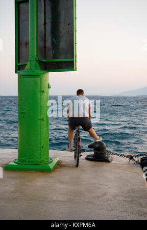 Un homme adulte sur son vélo sur un quai donne sur la mer Banque D'Images