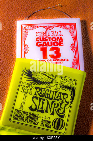 Un ensemble d'Ernie Ball regular slinky, manomètre, cordes guitare électrique, avec un dénoué string dépassant de sa personne paquet de papier. Made in USA. Banque D'Images