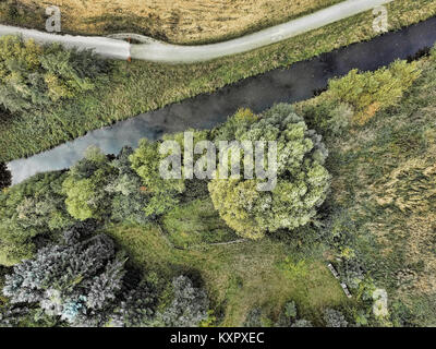 Résumé Vue aérienne de la pointe d'un ruisseau près d'une prairie avec un grand arbre vert isolé, fabriqué par drone Banque D'Images