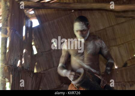 Avec un tambour Asmat. L'homme de la tribu de Asmat traditionnels avec la peinture du visage bat le tambour. 23 mai, 2016 Banque D'Images