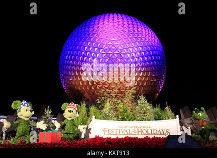 Disney's Epcot Center sphere éclairée la nuit pendant la saison des Fêtes avec Mickey, Minnie et Pluto personnages sculptures d'herbe . Banque D'Images