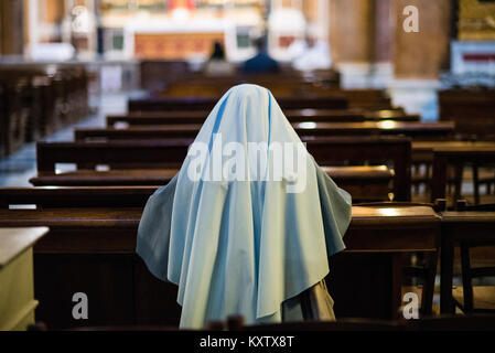 L'église, Rome, nonne prie dans l'église à genoux sur le banc, tôt le matin Banque D'Images