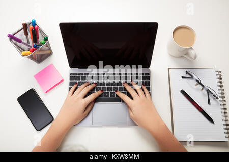 Femme utilisant un ordinateur portable à une table dans une vue de dessus de ses mains tapant Banque D'Images
