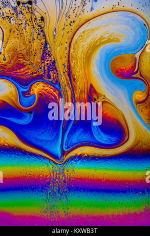 Des motifs d'interférence dynamiques vifs tourbillonnent sur un mince film de savon, où le liquide et la lumière qui s'écoulent créent des rubans lumineux de couleur et de mouvement abstrait Banque D'Images