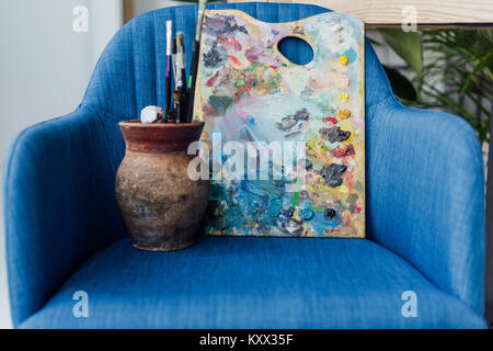 Creative bocal rempli avec pinceaux et palette de l'artiste d'un séjour sur fauteuil bleu Banque D'Images