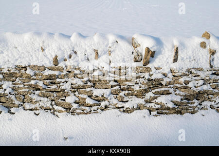 En pierre de Cotswold mur recouvert de neige. Cotswolds, Gloucestershire, Angleterre Banque D'Images