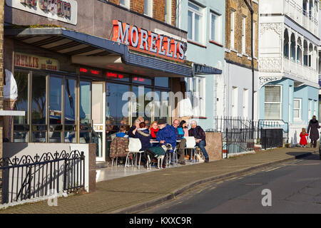 Les gens assis dehors Morellis ice cream parlour dans Broadstairs, Kent sur winters après-midi Banque D'Images