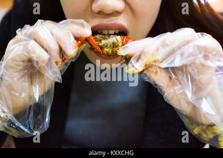 Asian woman eating une écrevisse avec des gants en plastique Banque D'Images