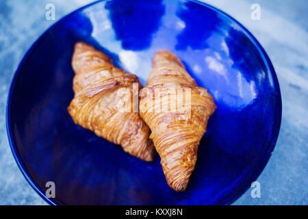 High angle portrait de deux croissants fraîchement cuits sur une plaque bleue. Banque D'Images