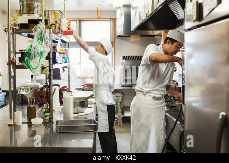 Deux chefs travaillant dans la cuisine d'un restaurant de sushi japonais. Banque D'Images