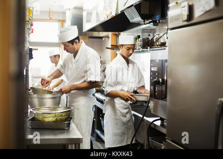 Deux chefs travaillant dans la cuisine d'un restaurant de sushi japonais. Banque D'Images