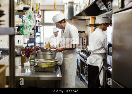 Deux chefs travaillant dans la cuisine d'un restaurant de sushi japonais. Banque D'Images