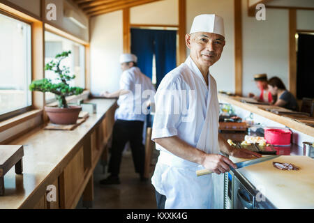 Deux chefs travaillant au comptoir dans un restaurant de sushi japonais. Banque D'Images