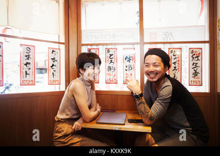 Deux personnes, souriant l'homme et la femme assis à une petite table dans un café. Banque D'Images