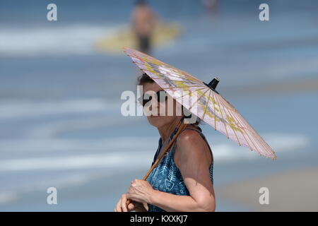 Femme avec parasol des tons de soleil sur plage Banque D'Images