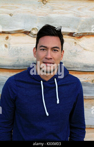Young man standing in front of wooden wall Banque D'Images