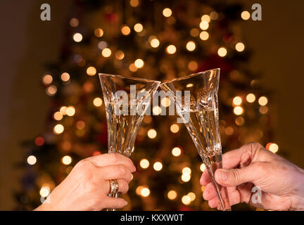 Deux flûtes à Champagne en cristal contre les lumières d'arbre de Noël Banque D'Images