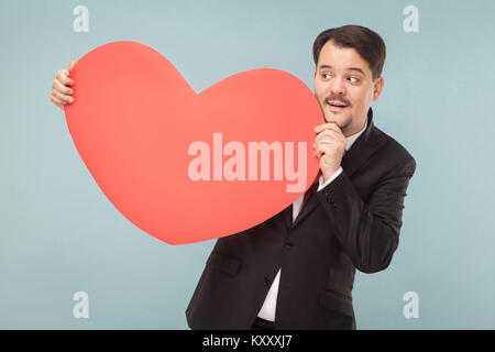 Le bonheur des profils businessman holding big red heart shape et souriant. Studio shot, isolé sur fond bleu clair Banque D'Images