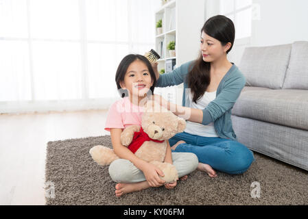 Jeune femme élégante à l'aide aider brosse smiling pretty girl peigner les cheveux des enfants. Banque D'Images