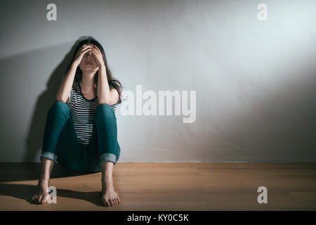 Jeune femme élégante ayant dépression trouble bipolaire Trouble sentiment de confusion assis sur un plancher en bois reposant sur fond blanc. Banque D'Images