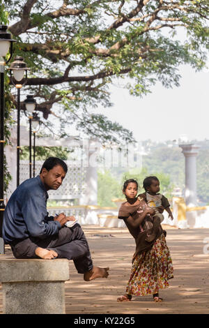 L'indifférence la racine de l'inégalité : Gentleman assis sur un banc semble loin d'un pauvre jeune fille habillée avec mesquinerie, tenant son frère. Banque D'Images