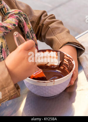 Mains d'un enfant jouer le pâtissier mélanger le chocolat dans un bol avant de le verser dans les moules à chocolat. Banque D'Images